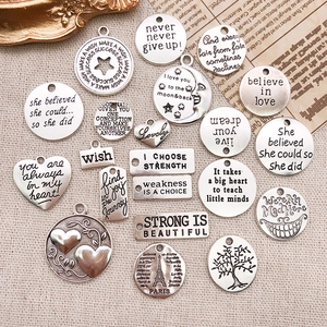 Macro view of vintage silver alloy charms with engraved motivational quotes for DIY jewelry
