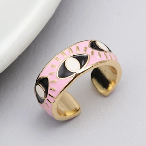Macro shot of gold-plated open ring with colorful enamel evil eye patterns on the band