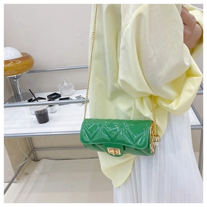 Close-up of green quilted cylindrical jelly bag with gold chain and pearl accent