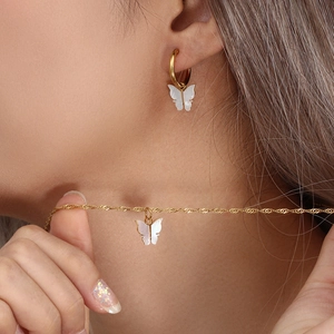 Detail of gold rope chain necklace and hoop earrings with white shell butterfly pendants