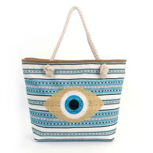 Striped canvas tote bag with evil eye embroidery and rope handles for beach travel