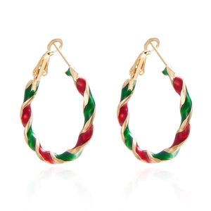 Close-up of twisted gold hoops with red and green enamel for Christmas holiday style