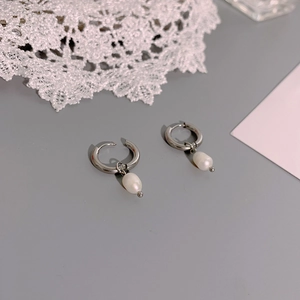 Close-up of elegant silver stainless steel hoop earrings with natural pearl pendants