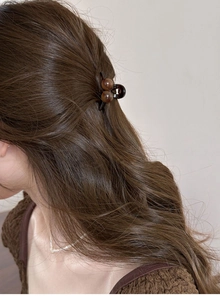 Vue rapprochée d'une petite pince à cheveux ambrée sur cheveux longs pour coiffage
