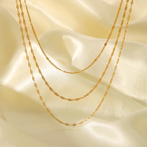 Detailed view of 18K gold layered stainless steel necklaces on soft beige silk fabric