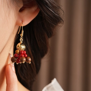 Close-up of Bohemian drop earrings with red and wood beads on a model's ear