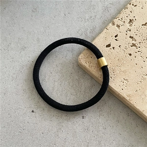 Macro shot of black high-elastic hair tie with twill texture and gold metal connector