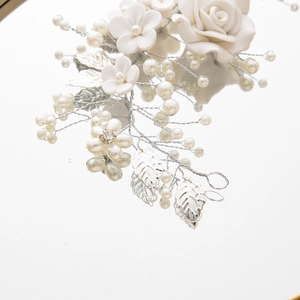 Macro detail of bridal vine with white ceramic flowers, silver leaves, and pearls