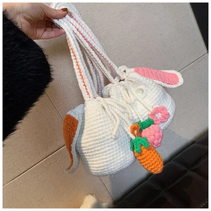 Detail of handmade crochet rabbit bucket bags with carrot and flower charms