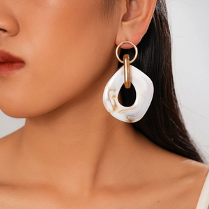 Close-up of bohemian resin earrings with amber textures on model for fashion detail