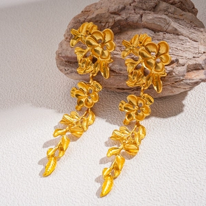 Boucles d'oreilles vintage dorées à fleurs et feuilles sur bois et fond blanc