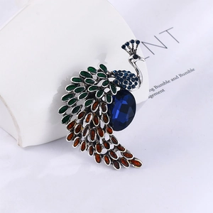 Détail de broche paon vintage avec pierres bleues et émail vert sur support céramique