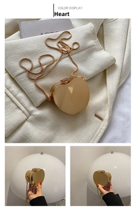Macro detail of a heart-shaped gold evening bag with metallic finish and snake chain