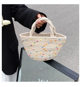 Detail of hand-woven straw bucket bag with colorful dots and stylish cotton rope handles