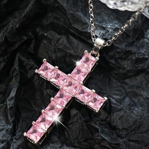 Pink zircon cross pendant necklace with silver chain on black textured background