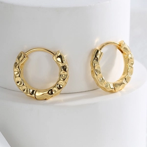 Detail of irregular hammered texture on gold-plated brass hoop earrings with metallic gloss