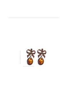 Macro detail of vintage bow earrings featuring bronze metal and oval amber rhinestones