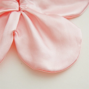Close-up of pink satin fabric scrunchie detail showing soft glossy texture and folds