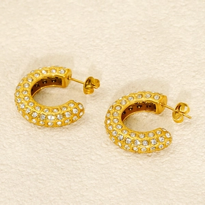 Vue détaillée de boucles d'oreilles C dorées avec cristaux pavés et fermoirs papillon
