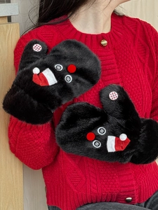 Close-up of black plush Christmas mittens with snowman details and red hats