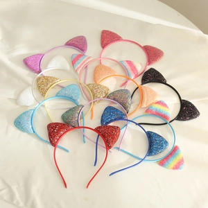 Close-up of glitter cat ear headbands in various candy colors on beige fabric background