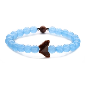 Macro detail of beaded bracelet with light blue beads and a brown goldstone butterfly