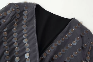 Detailed macro view of the grey V-neck sequin embellishments on ribbed fabric texture