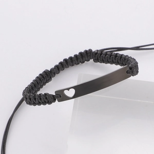 Macro shot of black matte metal bar with heart cutout on adjustable braided wax rope bracelet