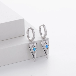 Detail of silver heart drop earrings with blue opal evil eye and white zircon inlay