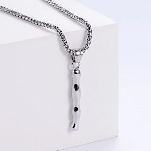 Détail du pendentif argenté style métal liquide avec chaîne box sur bloc blanc
