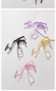 Detail view of four multi-colored translucent eyelash curlers in a diagonal arrangement