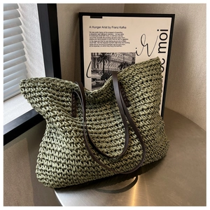 Close-up of moss green woven tote bag with brown leather straps on a metal table