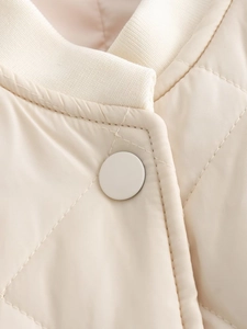 Détail de la veste matelassée blanc cassé avec col côtelé et bouton-pression mat