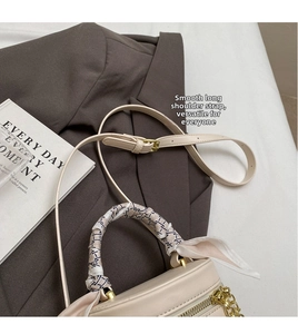 Detail of cream woven bucket bag with decorative silk scarf and gold zipper accents