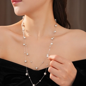 Detail view of double-layer silver pearl necklace worn by a model with an off-shoulder top