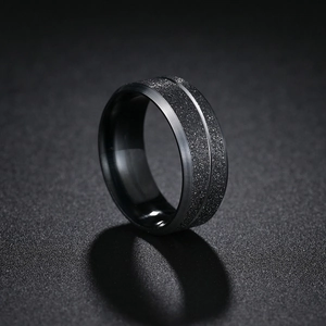 Macro shot of men's black stainless steel ring with brushed edges and matte sandblasted inlay