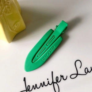 Macro view of green matte hair clip showing non-slip grooves and UANODIAM engraved detail