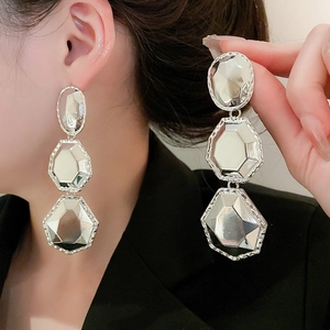 Gros plan détaillé de boucles d'oreilles argentées géométriques portées par un mannequin