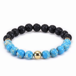 Macro shot of 8mm natural malachite and black lava stone beads with a golden accent
