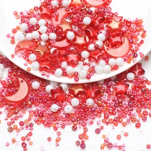 Macro shot of red star and moon DIY beads with white seed beads on a white tray