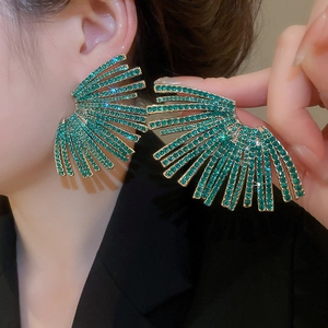 Macro shot of oversized fan-shaped emerald rhinestone earrings on a golden base