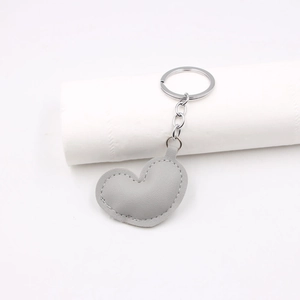 Close-up of grey heart-shaped PU leather keychain with metal ring on a white display