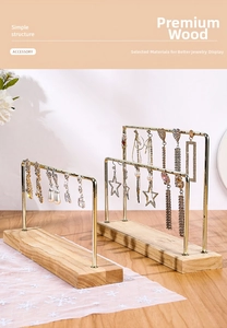 Detail of minimalist metal earring display stands with natural wood bases in gold finish