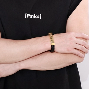 Detailed macro of men's braided leather bracelet featuring a gold magnetic metal clasp