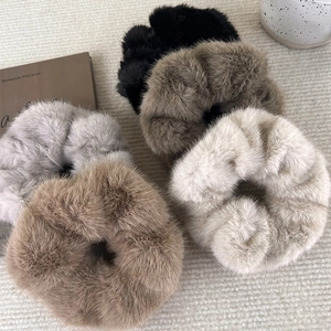 Faux mink fur scrunchies in five autumn colors set on a textured beige background