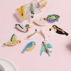 Detail of colorful bird-shaped acetate hair clips with golden metal duckbill clips