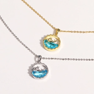Elegant whale tail pendant necklace with blue gemstone in gold and silver finishes