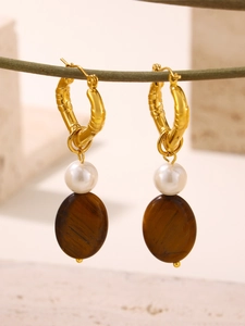 Macro view of gold bamboo hoops with white pearls and oval brown tiger eye charms