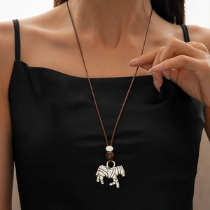 Detail of silver zebra pendant on dark brown cord necklace worn by a model