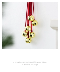 Close-up of golden Christmas bells with star cutouts and elegant red silk ribbons